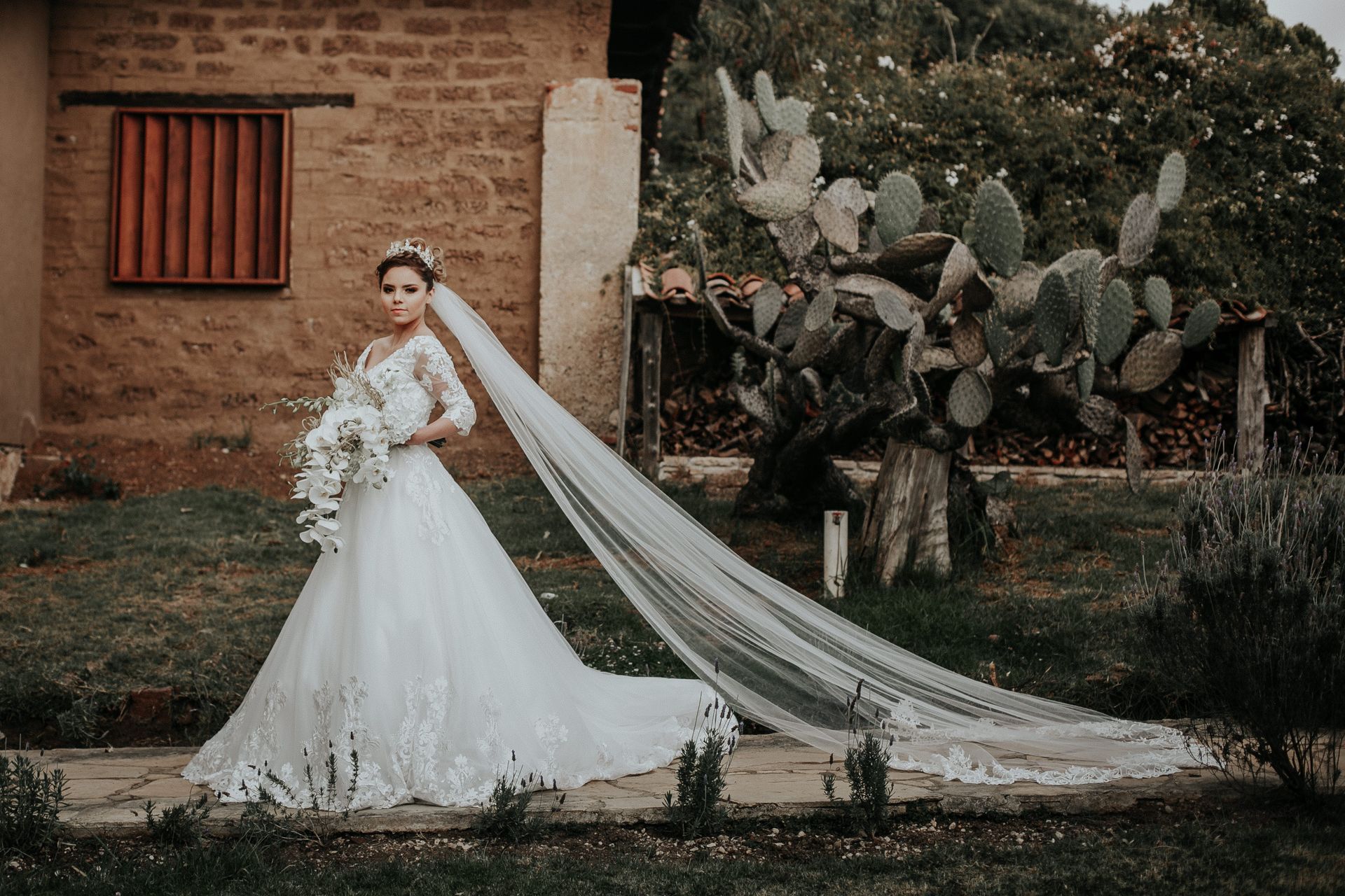The bride is wearing a long veil and holding a bouquet of flowers.