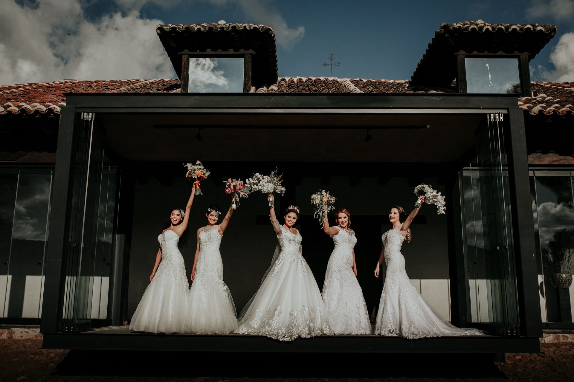 A group of women in wedding dresses are standing in front of a building.