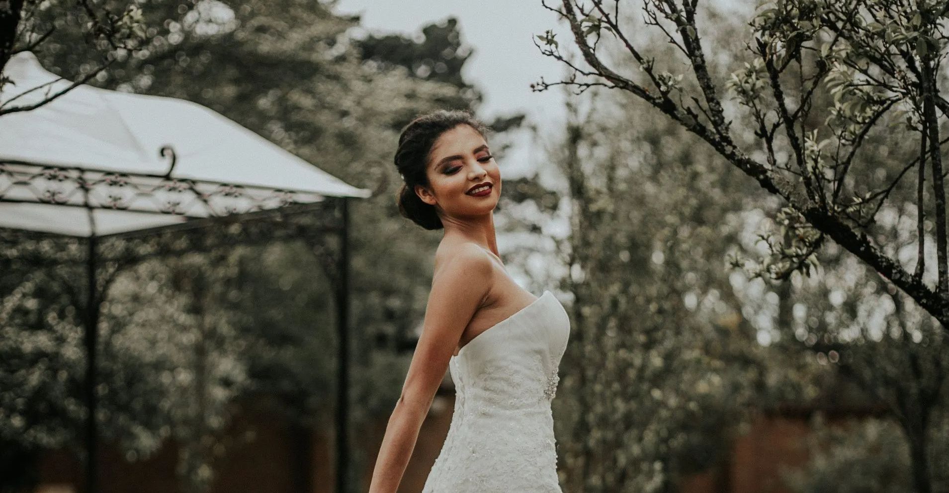 A woman in a wedding dress is standing in front of a gazebo.