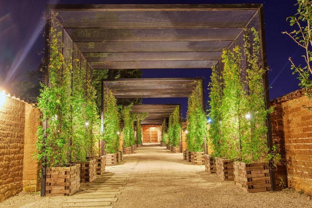 A wooden walkway lined with trees and brick walls at night.