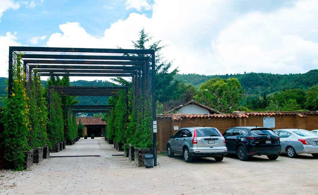 A parking lot with cars parked under a pergola.