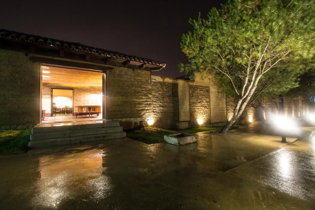A house is lit up at night with trees in front of it.