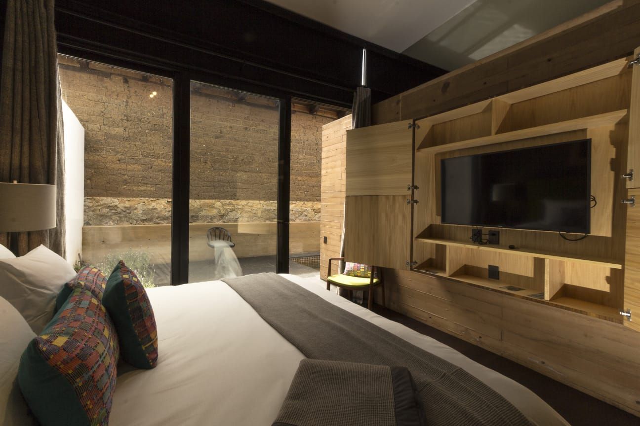 Un dormitorio con una cama grande y un televisor de pantalla plana en la pared.