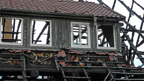 Partially burned wooden building with missing windows and damaged roof.