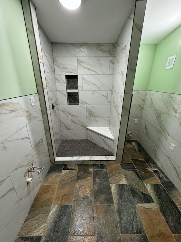 Modern tiled shower stall with gray marble walls, green side walls, and stone-look flooring