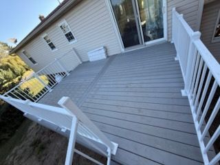 Tilted view of a white deck with railings beside a house, overlooking a grassy yard