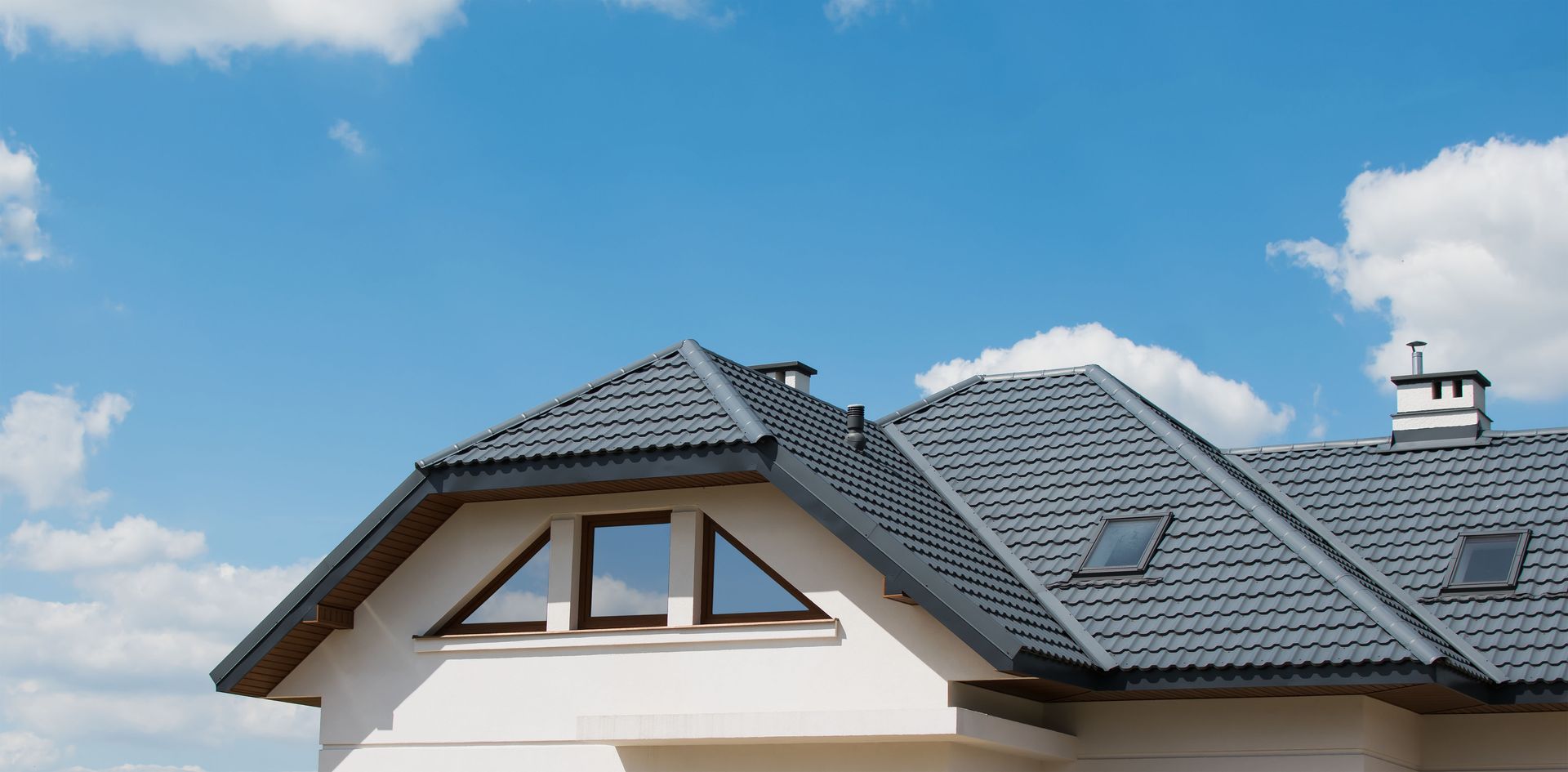 House with gray roof against a blue sky with clouds