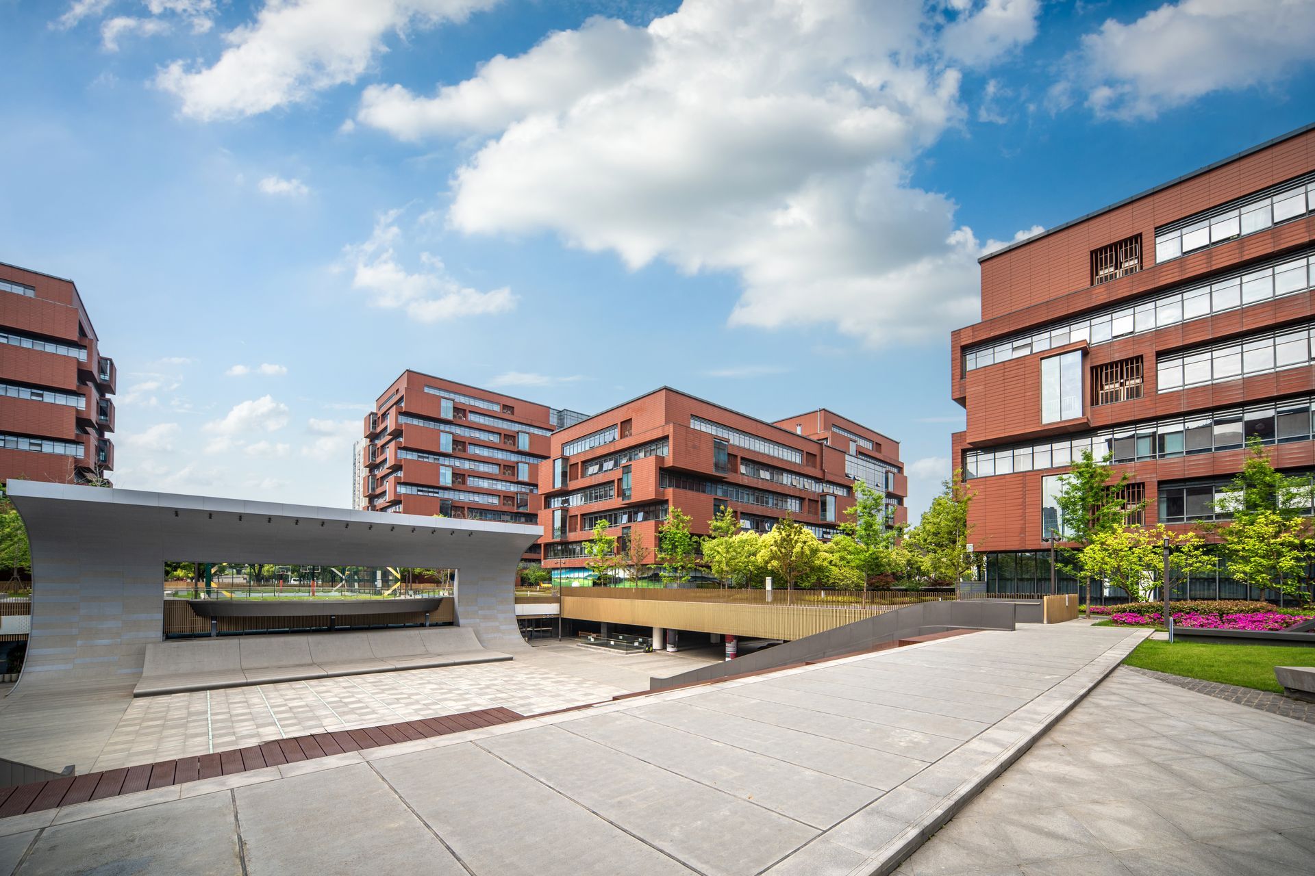Modern brick campus courtyard with benches, planters, and a blue sky