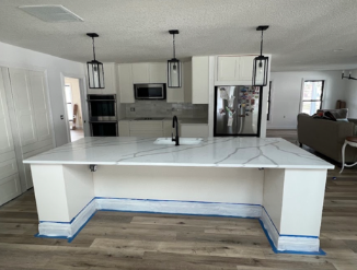 Modern kitchen with white island, marble countertop, pendant lights, and stainless steel appliances