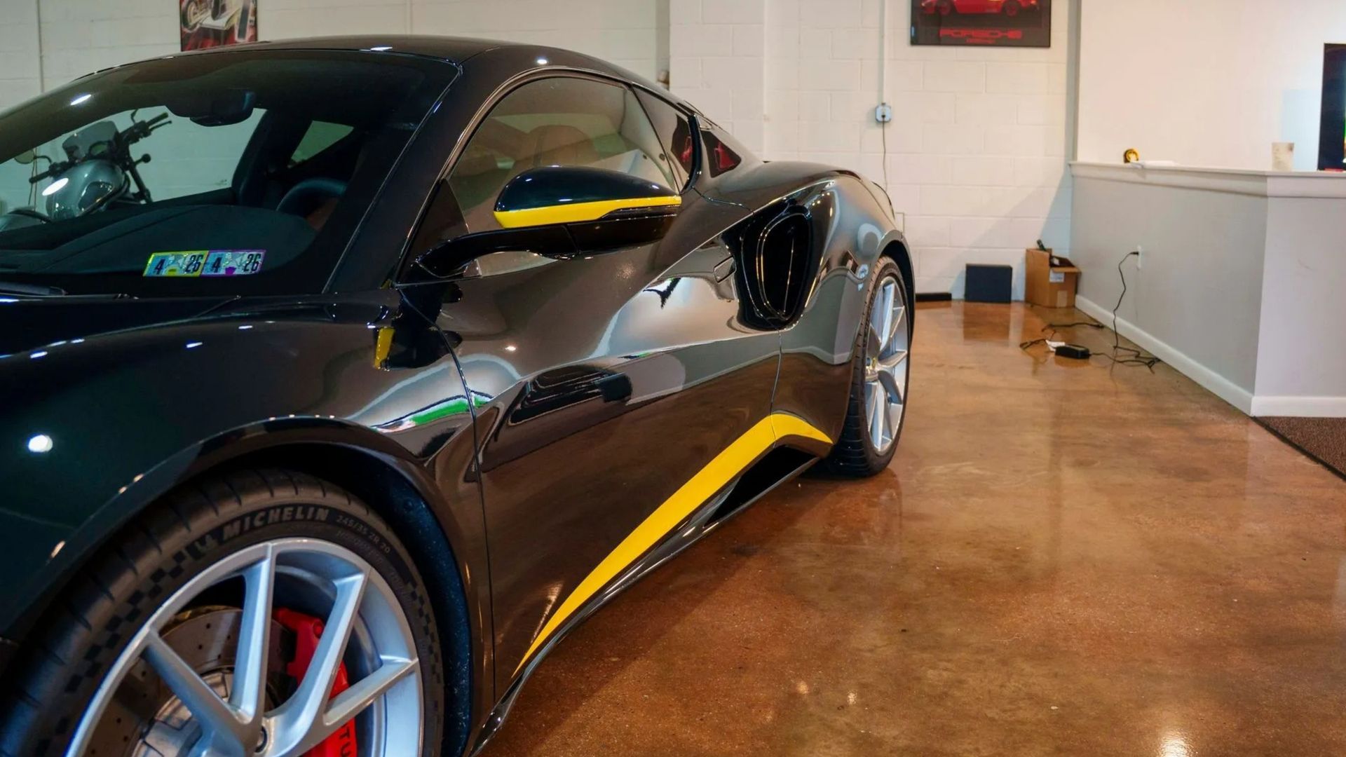 Black sports car with yellow accents parked indoors on a polished garage floor