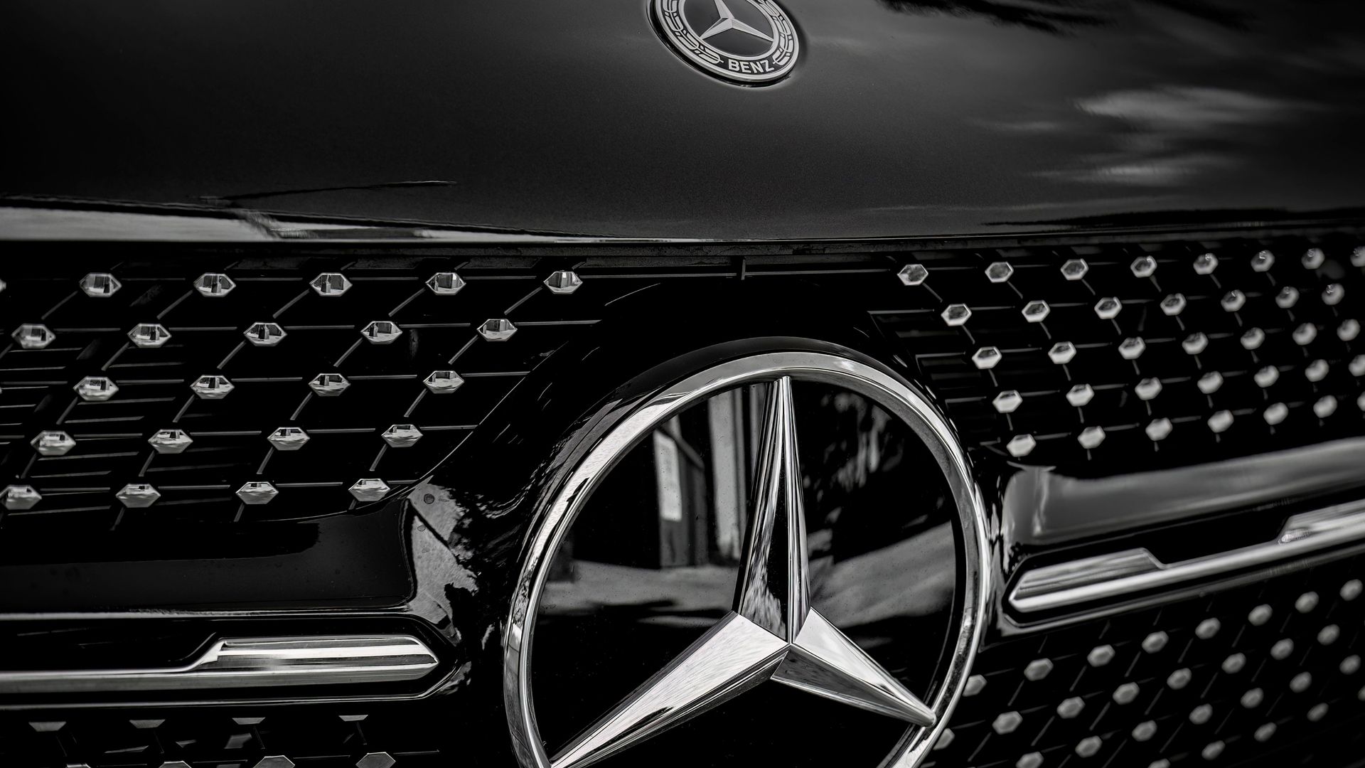 Close-up of a black Mercedes-Benz grille with chrome emblem and hood ornament