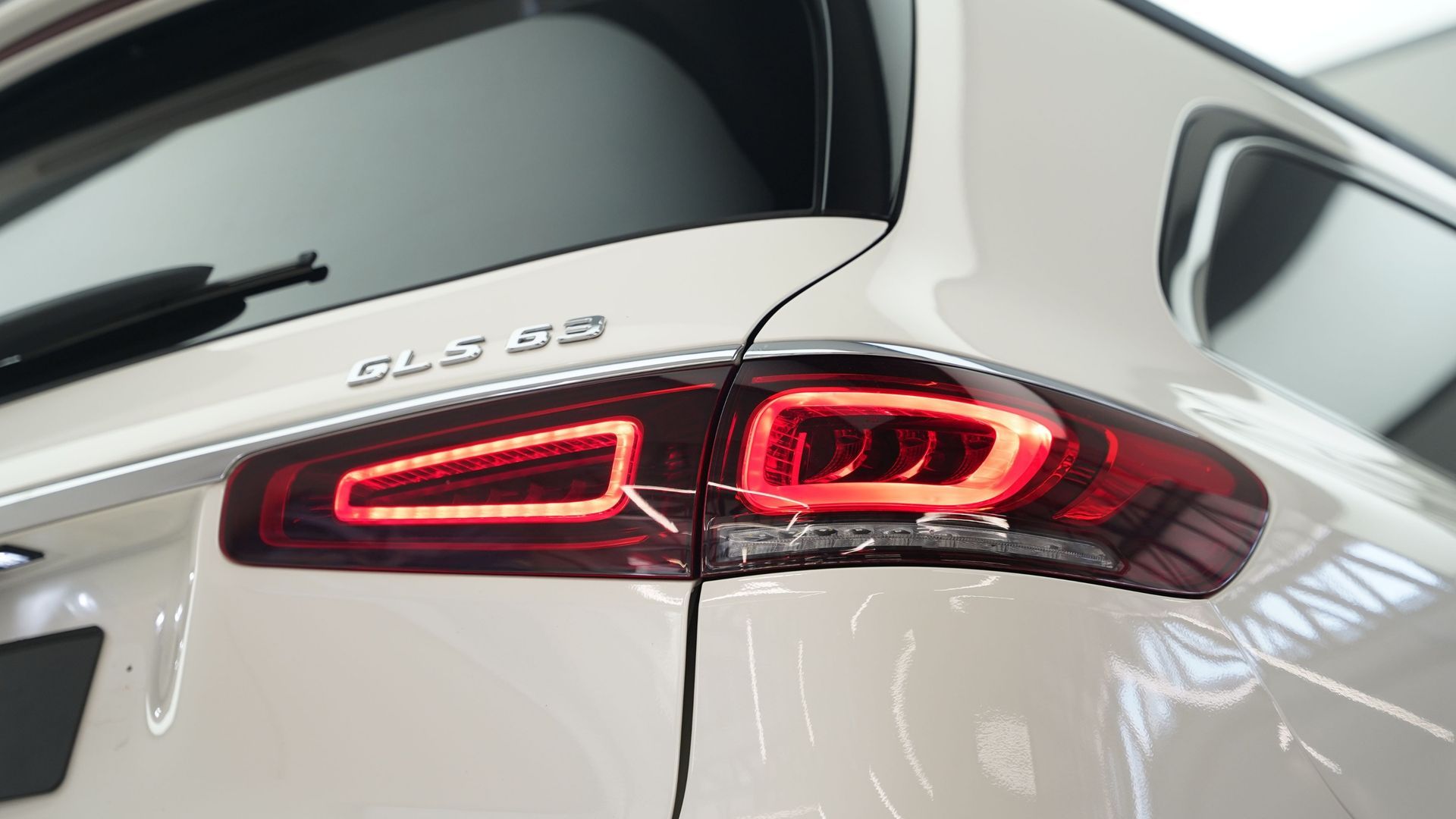 Close-up of a white Audi Q3’s rear, showing illuminated red taillights.
