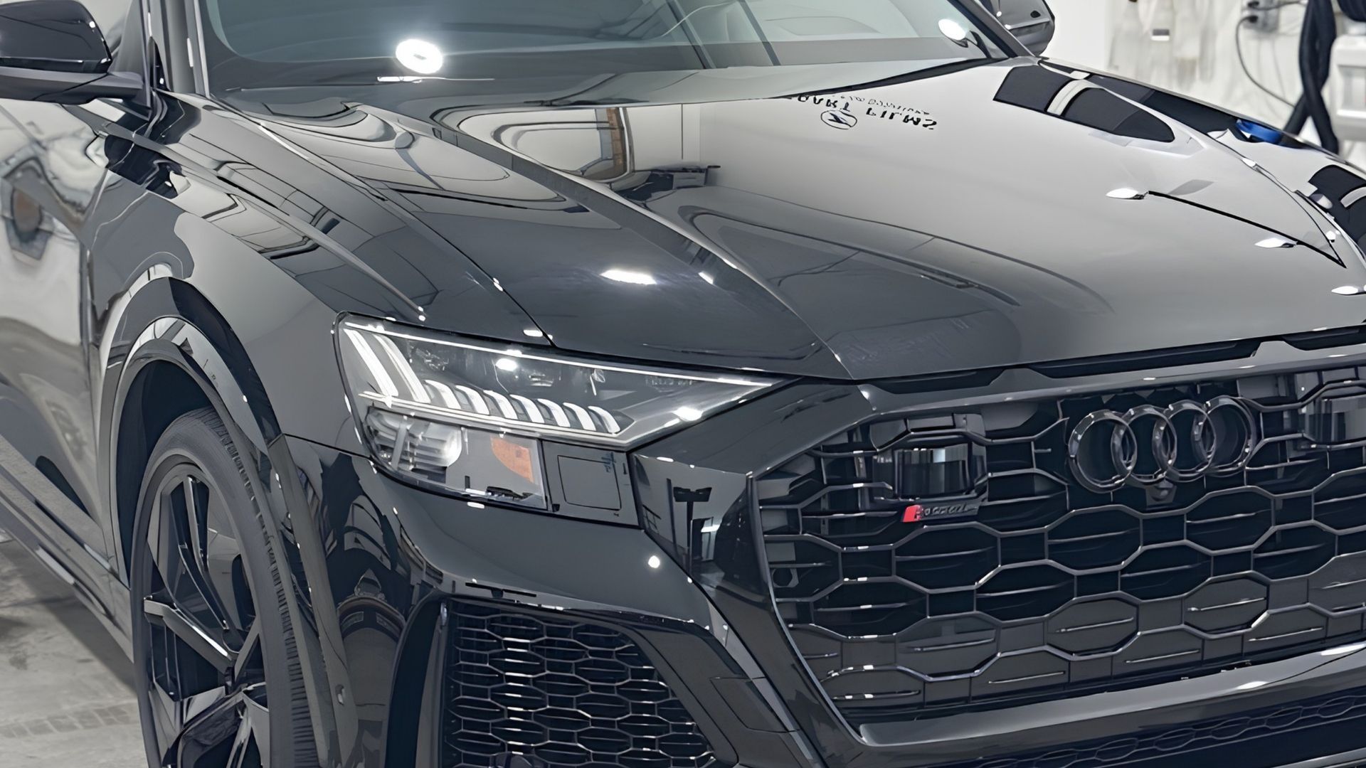 Close-up of a black Audi SUV front, showing the grille and headlights in a showroom