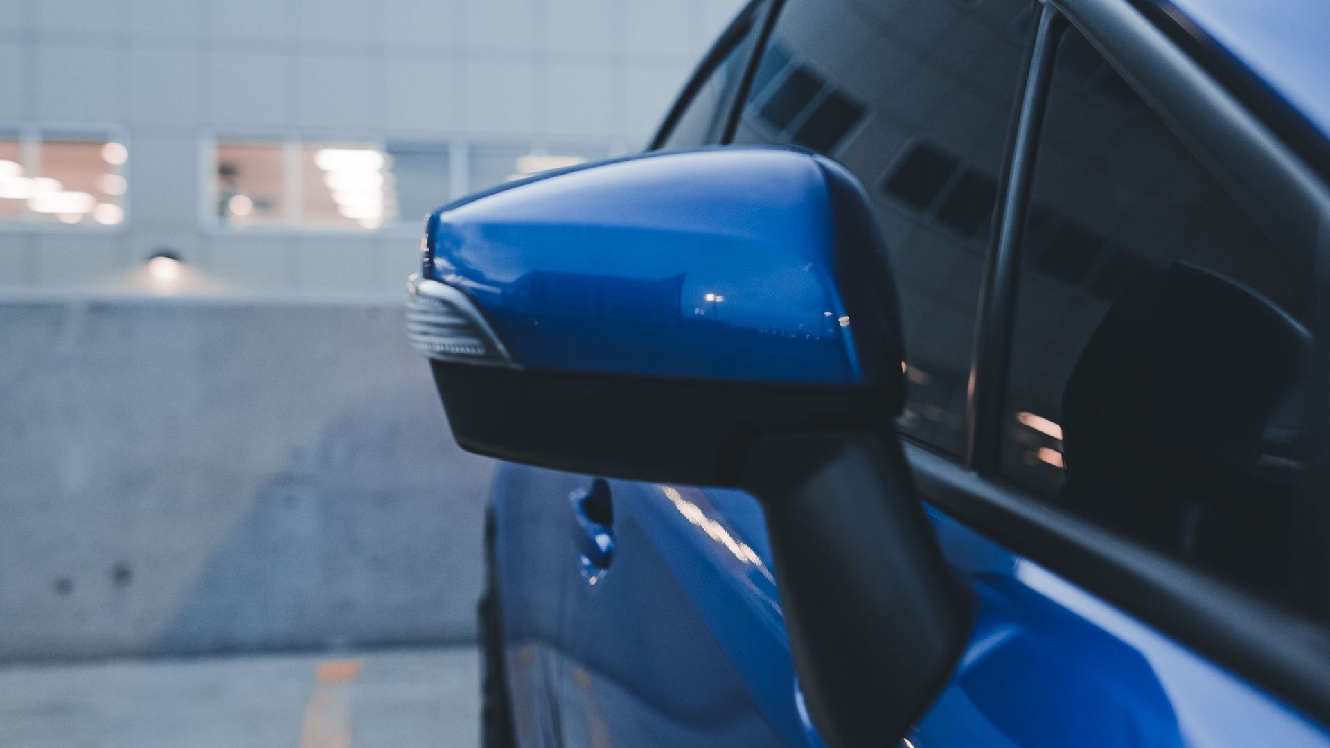Blue car side mirror on a parked vehicle in a garage setting