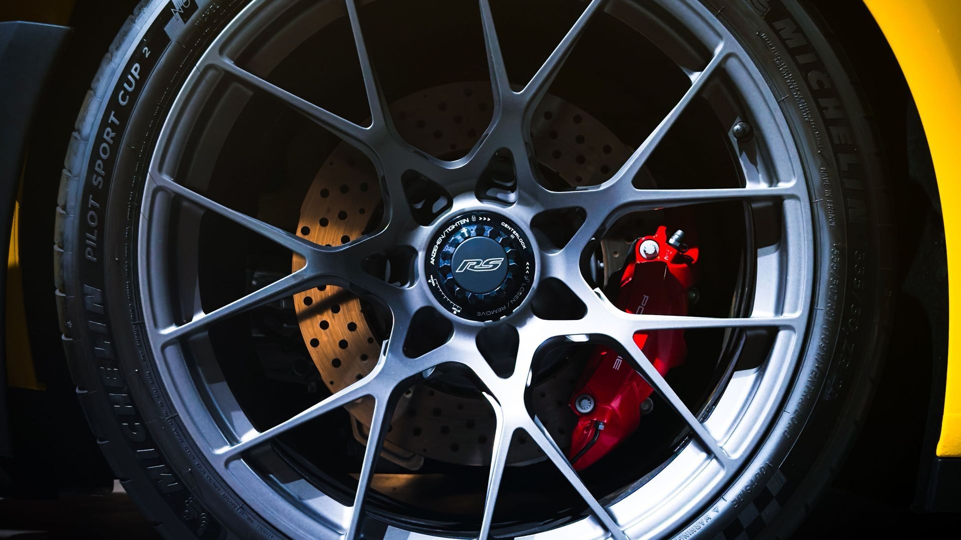 Close-up of a silver alloy car wheel with red brake caliper and drilled brake disc