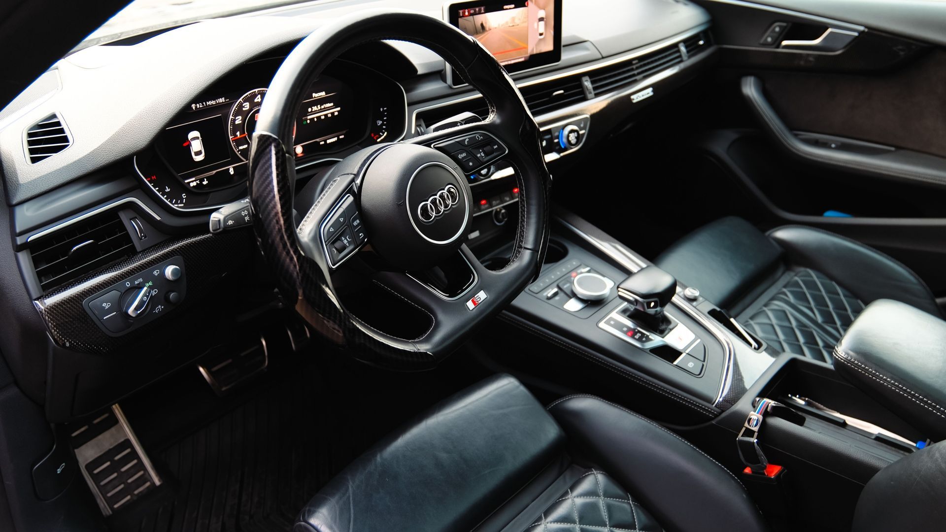 Black luxury car interior with leather seats, steering wheel, dashboard, and center console.