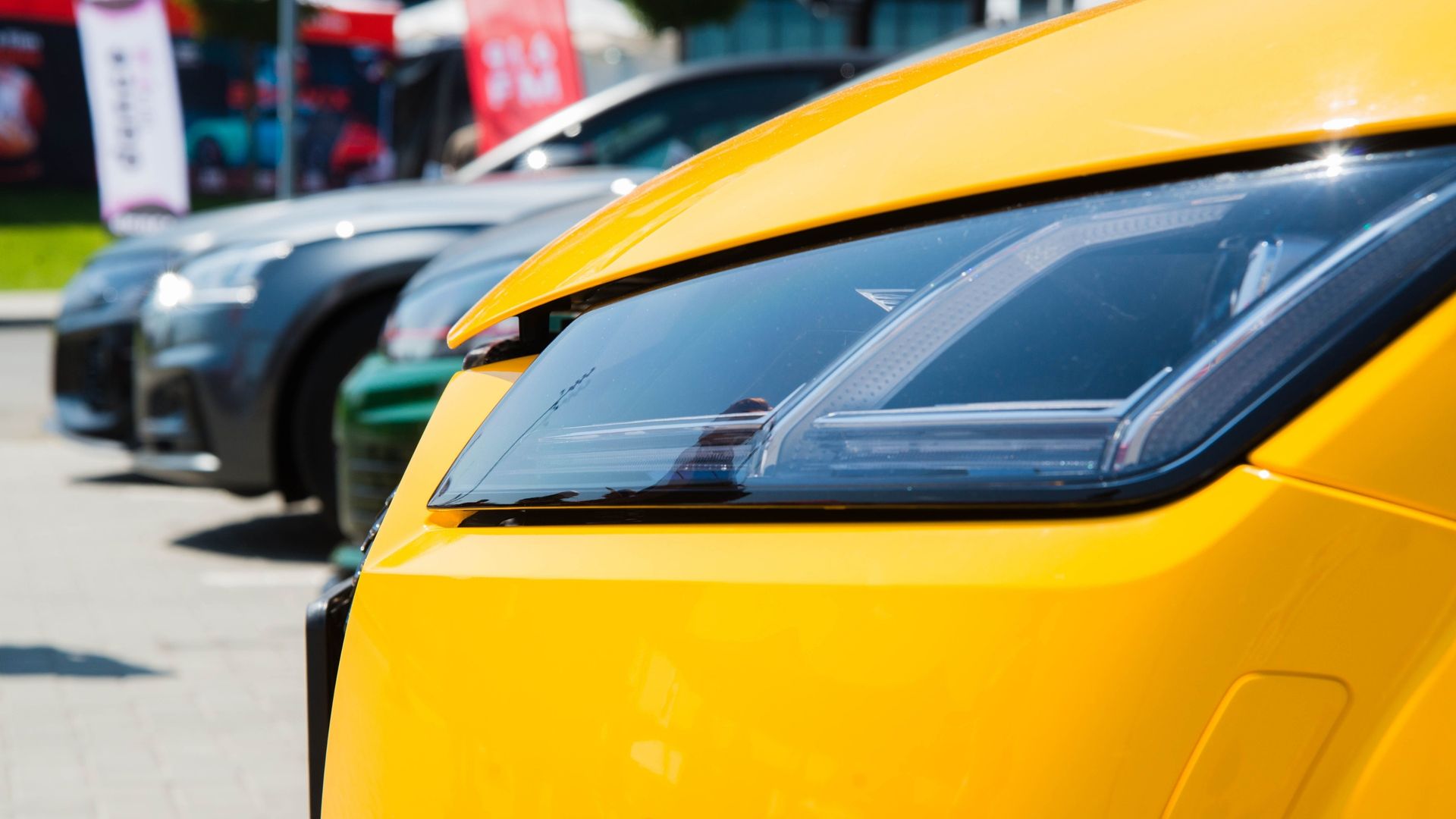 Close-up of a yellow sports car parked with other cars in a lot