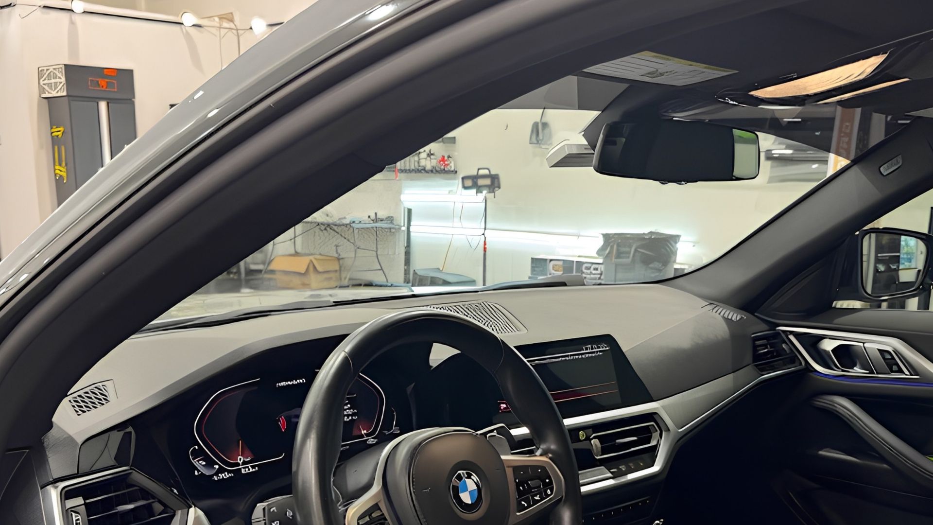 Interior of a BMW sedan, showing the steering wheel and dashboard in a garage or service bay