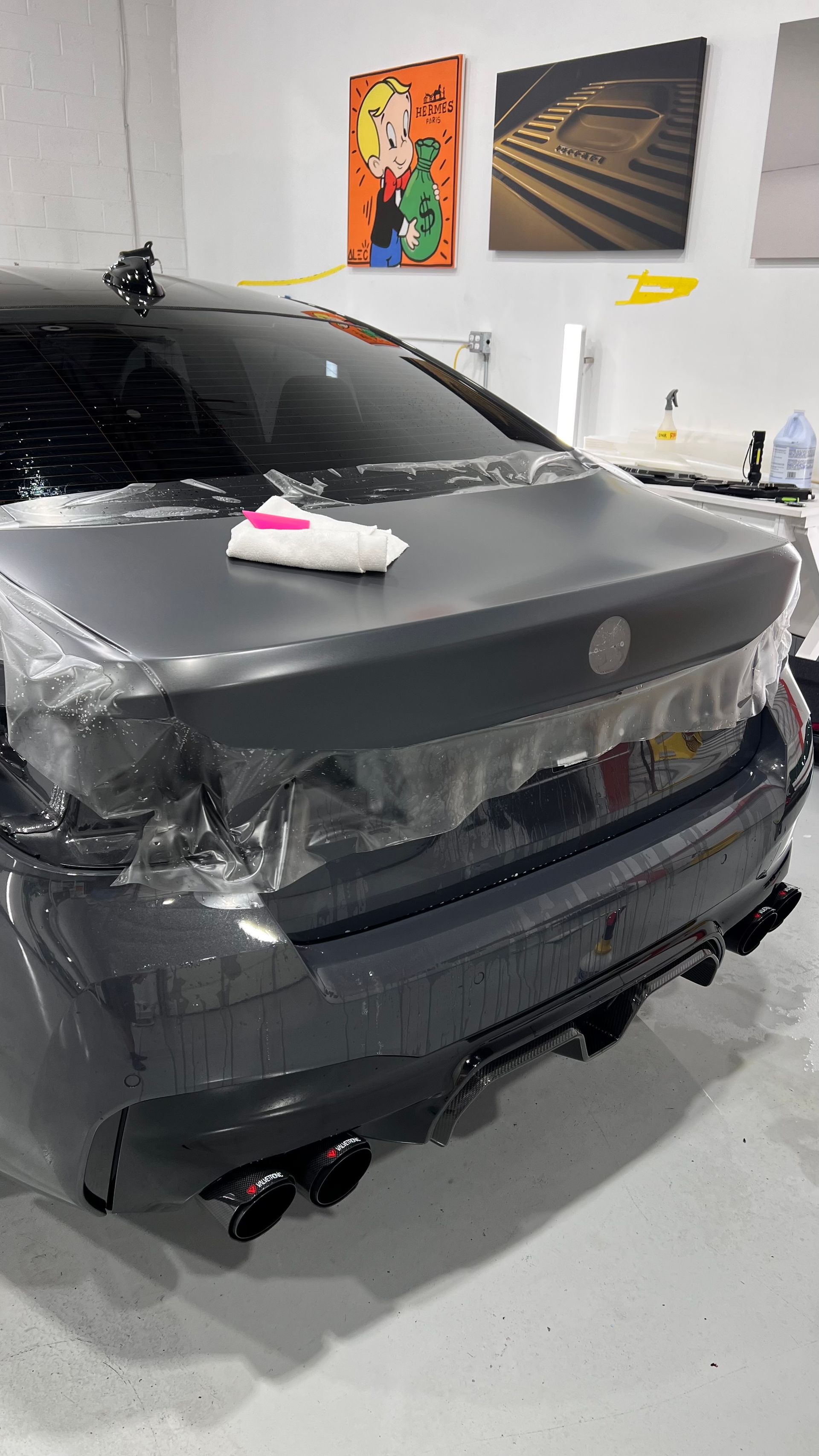 A car is wrapped in plastic and sitting in a garage.