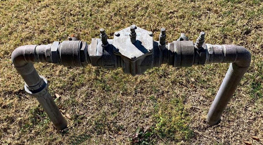 Metal Water Backflow Preventer Valve With Pipes, Outdoors on Grass — Hunter Plumbing And Hotwater in Port Stephens, NSW