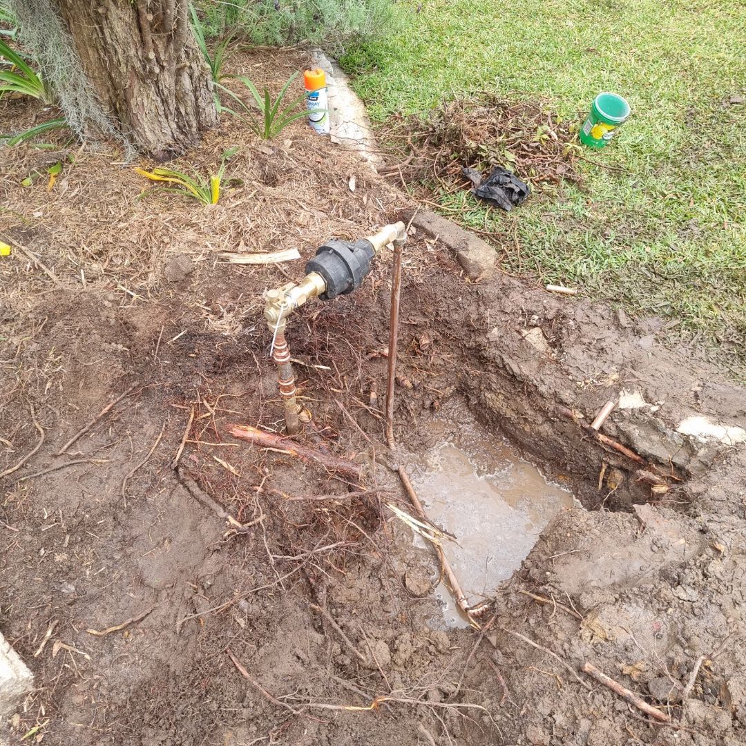 Partially Dug Muddy Hole Reveals a Water Pipe Connected to a Black Fitting — Hunter Plumbing And Hotwater in Tanilba Bay, NSW