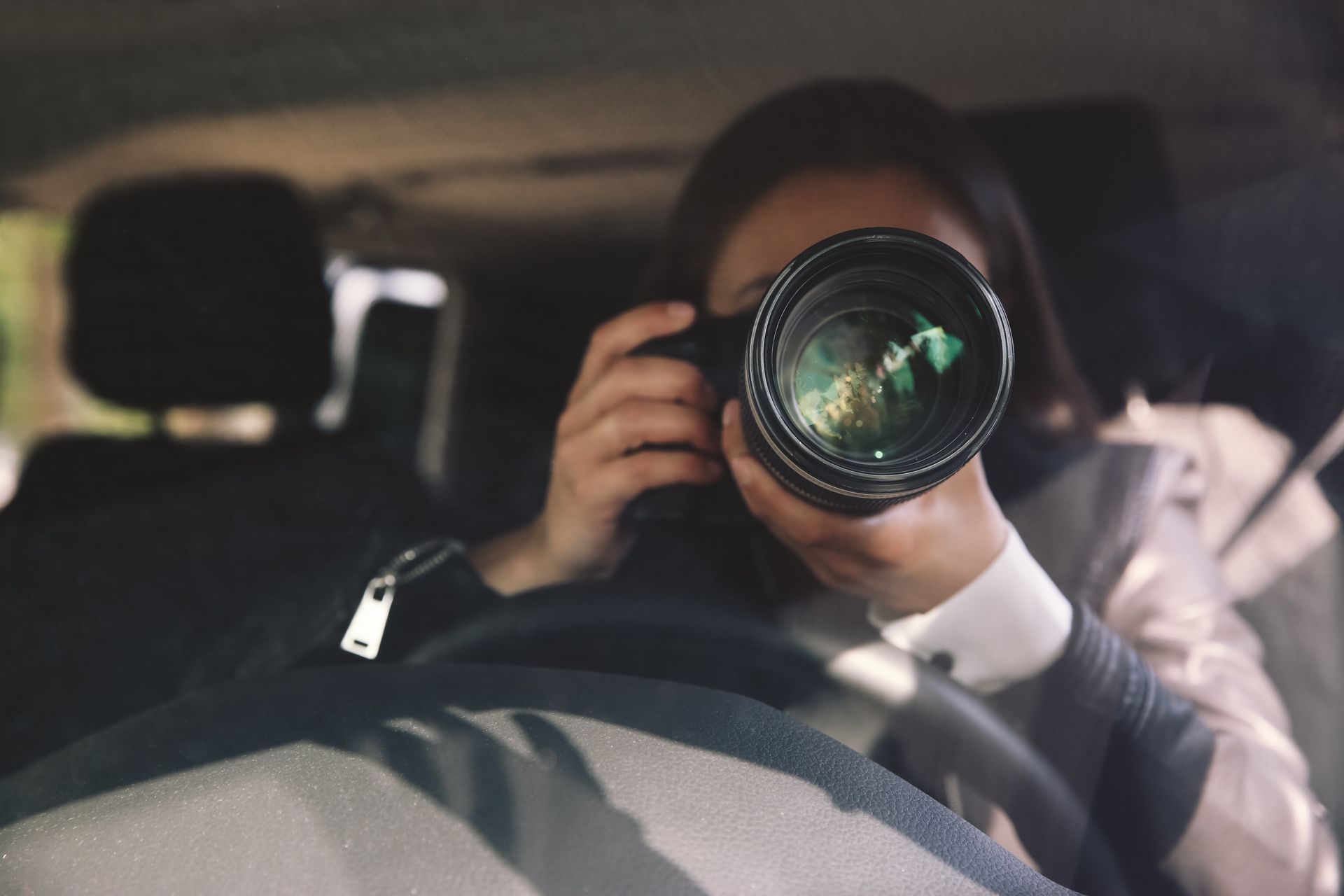 Private investigator conducting spouse surveillance from car using professional camera lens. Private investigator conducting spouse surveillance from car using professional camera lens.