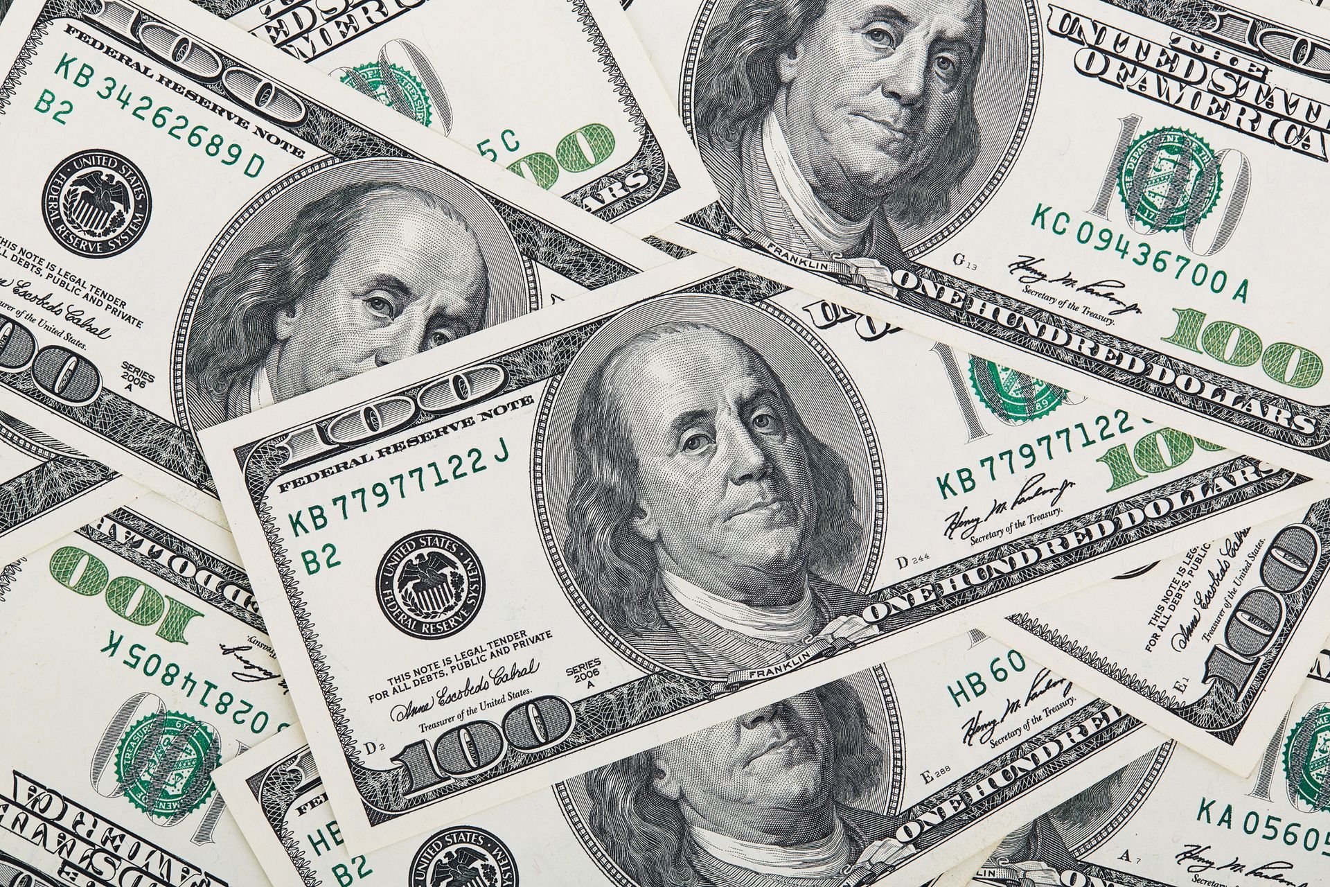 Scattered US $100 bills, showing portraits of Benjamin Franklin.