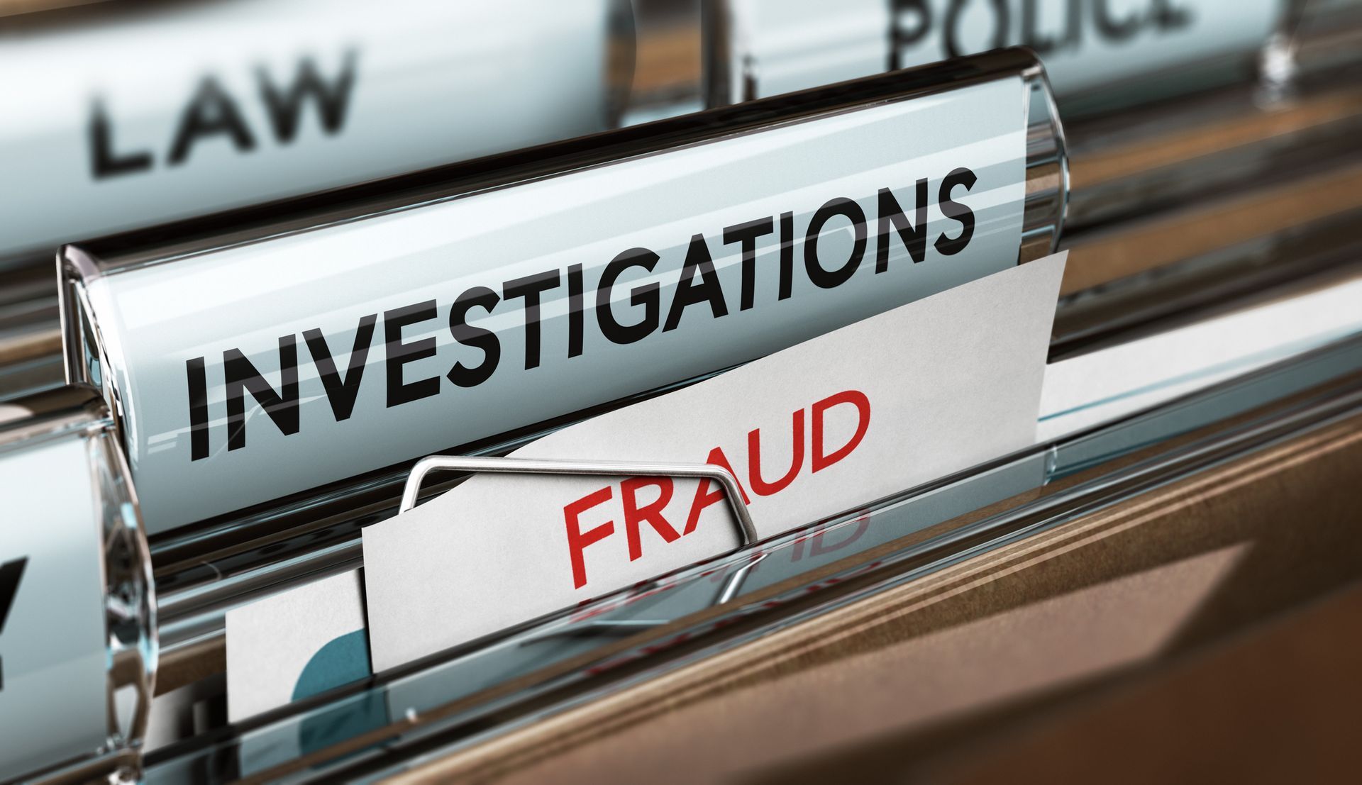 Close-up of file tabs labeled investigations, fraud, law, and police in an office setting.