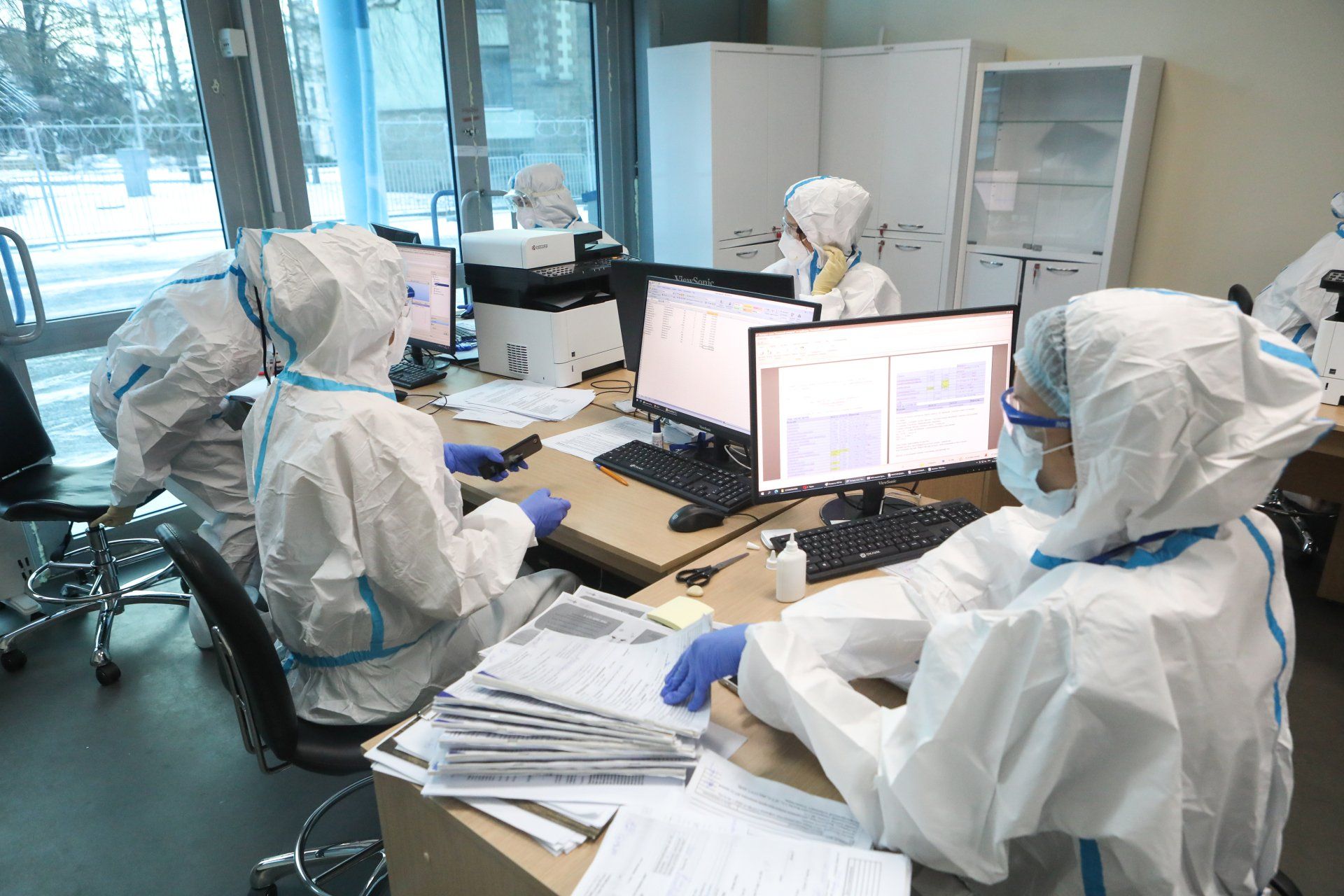 Office workers in hasmat suits at their desks - comical image