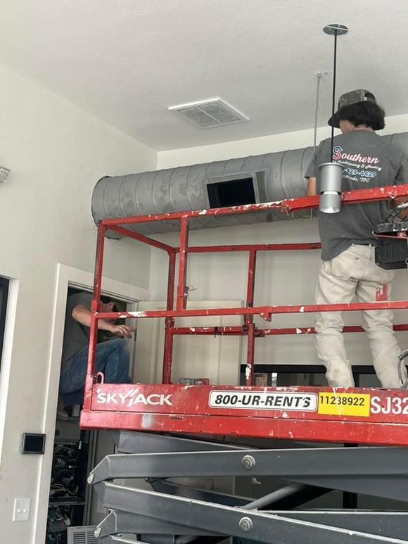 A man is standing on a scissor lift in a room.