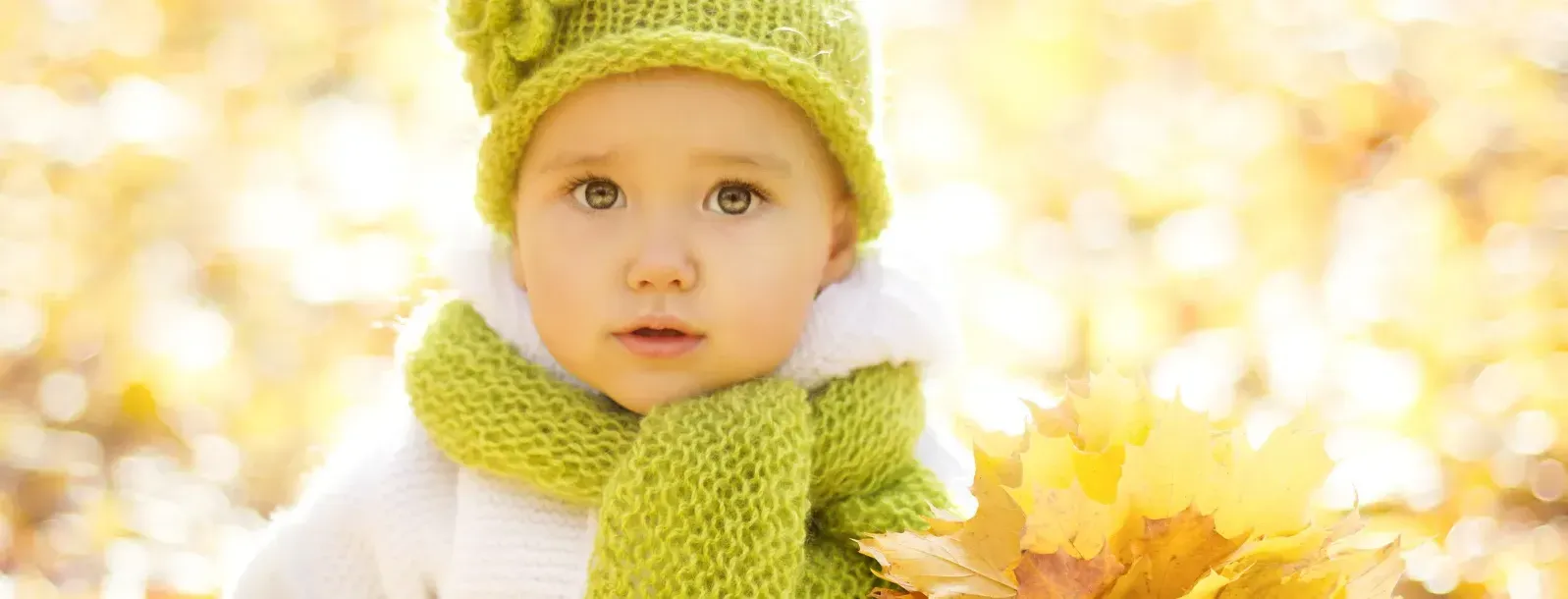 Baby wearing a green cap and scarf.