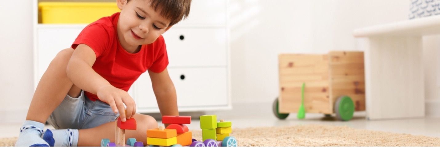 Child playing with colorful toy blocks on a carpet in a bright room
