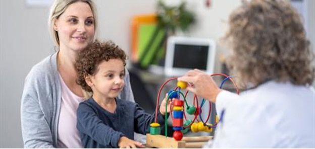 Parent and child play with a therapist using a colorful bead maze in a bright room
