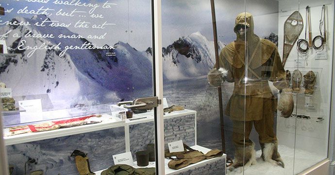 Museum display: Antarctic explorer's gear, including a suit and tools, against a snowy backdrop.