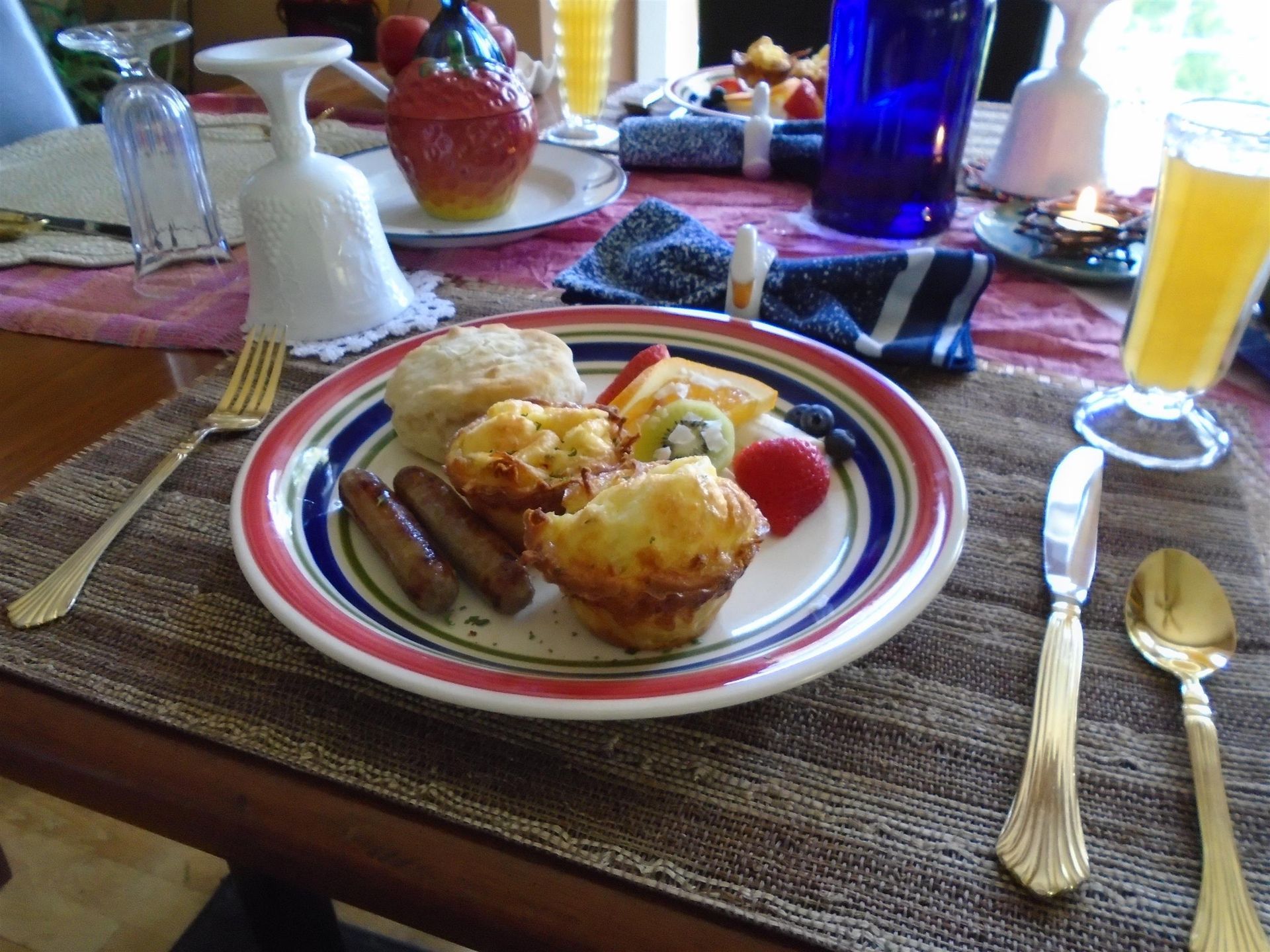 Breakfast plate with muffins, fruit, and orange juice on a set dining table