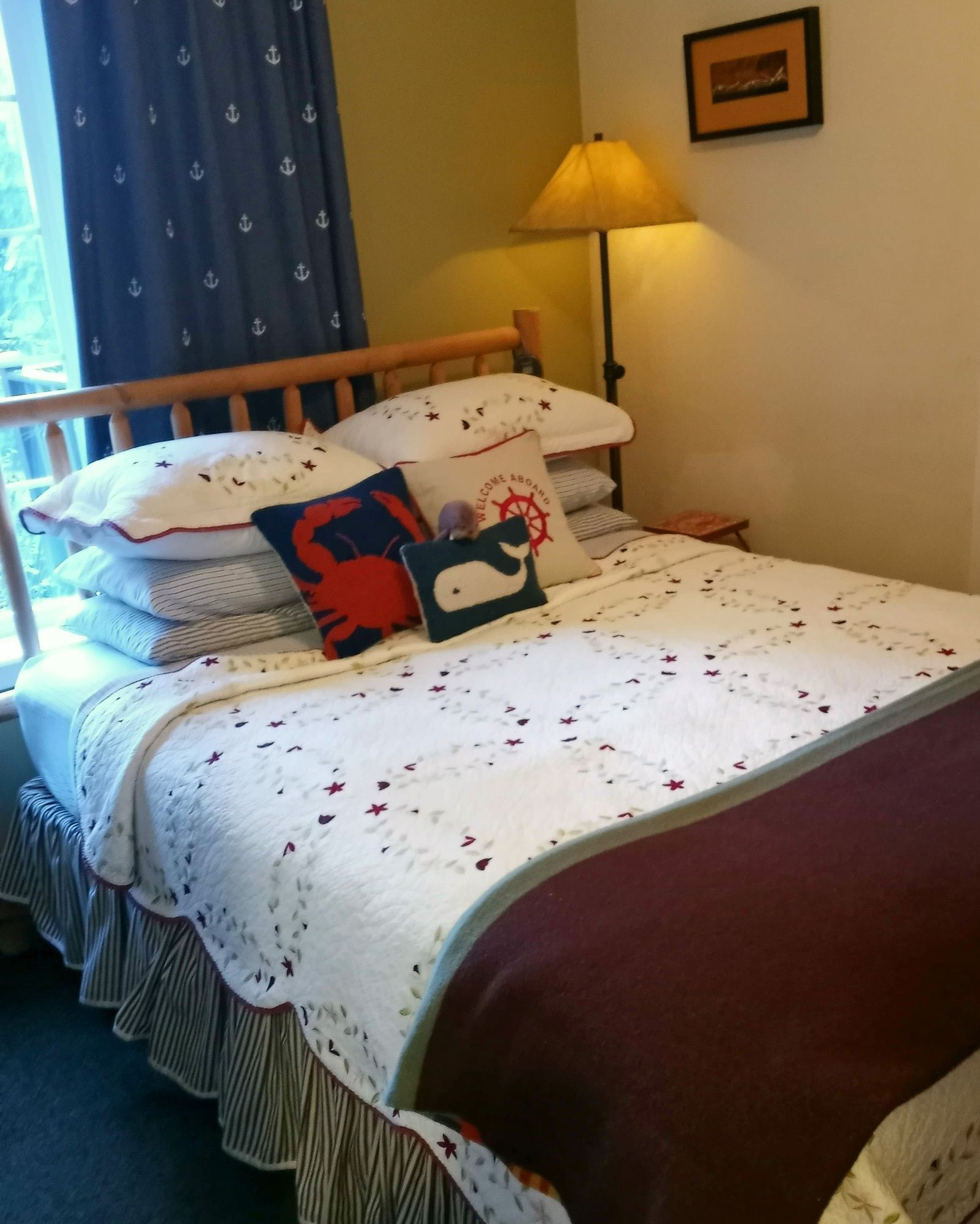 Cozy bedroom with a neatly made bed, blue curtains, and a lit floor lamp.