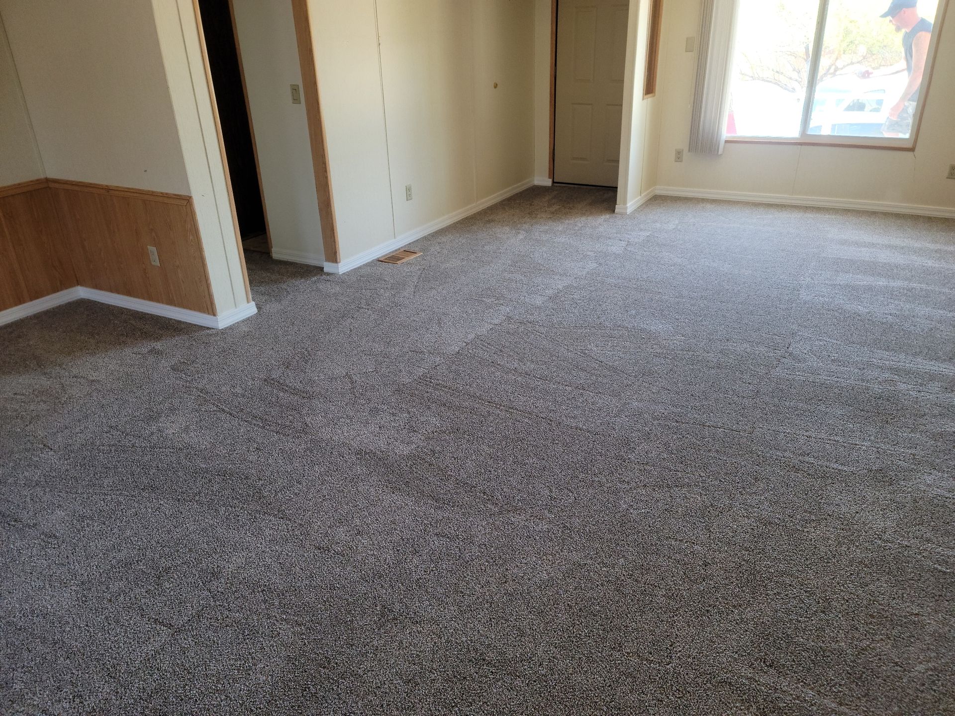 Empty carpeted room with beige walls, a closet, and a bright window.