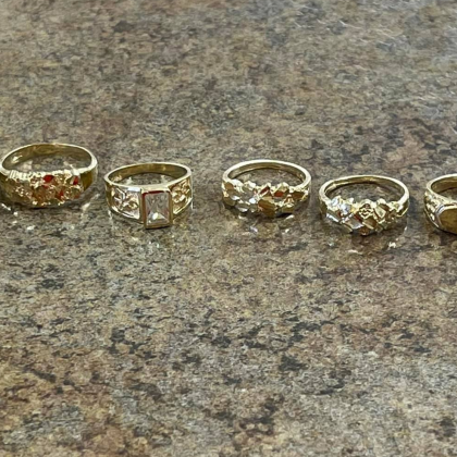 A group of gold rings are lined up on a table.