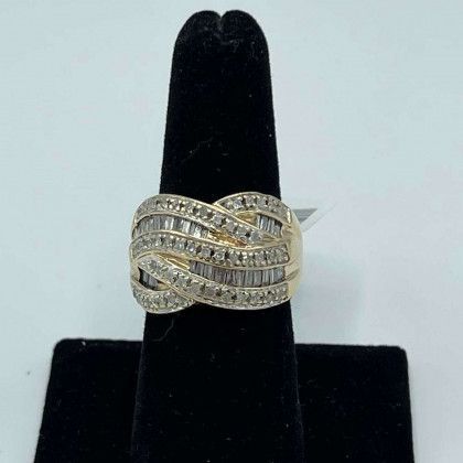 A gold ring with diamonds is sitting on a black velvet ring holder.