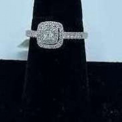 A diamond ring is sitting on top of a black velvet ring holder.