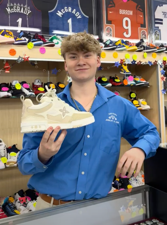 A man in a blue shirt is holding a white shoe