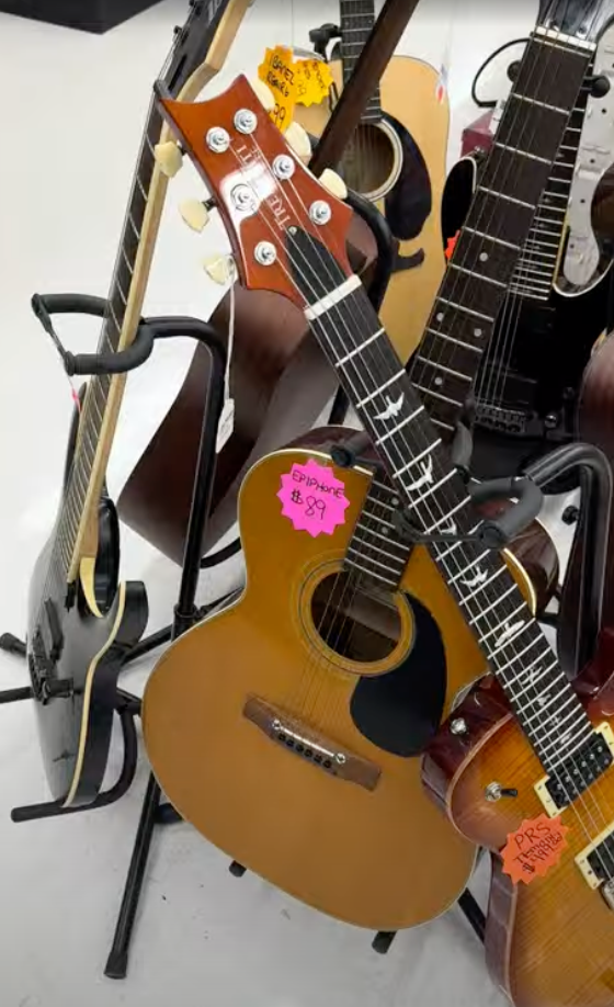 A bunch of guitars are stacked on top of each other