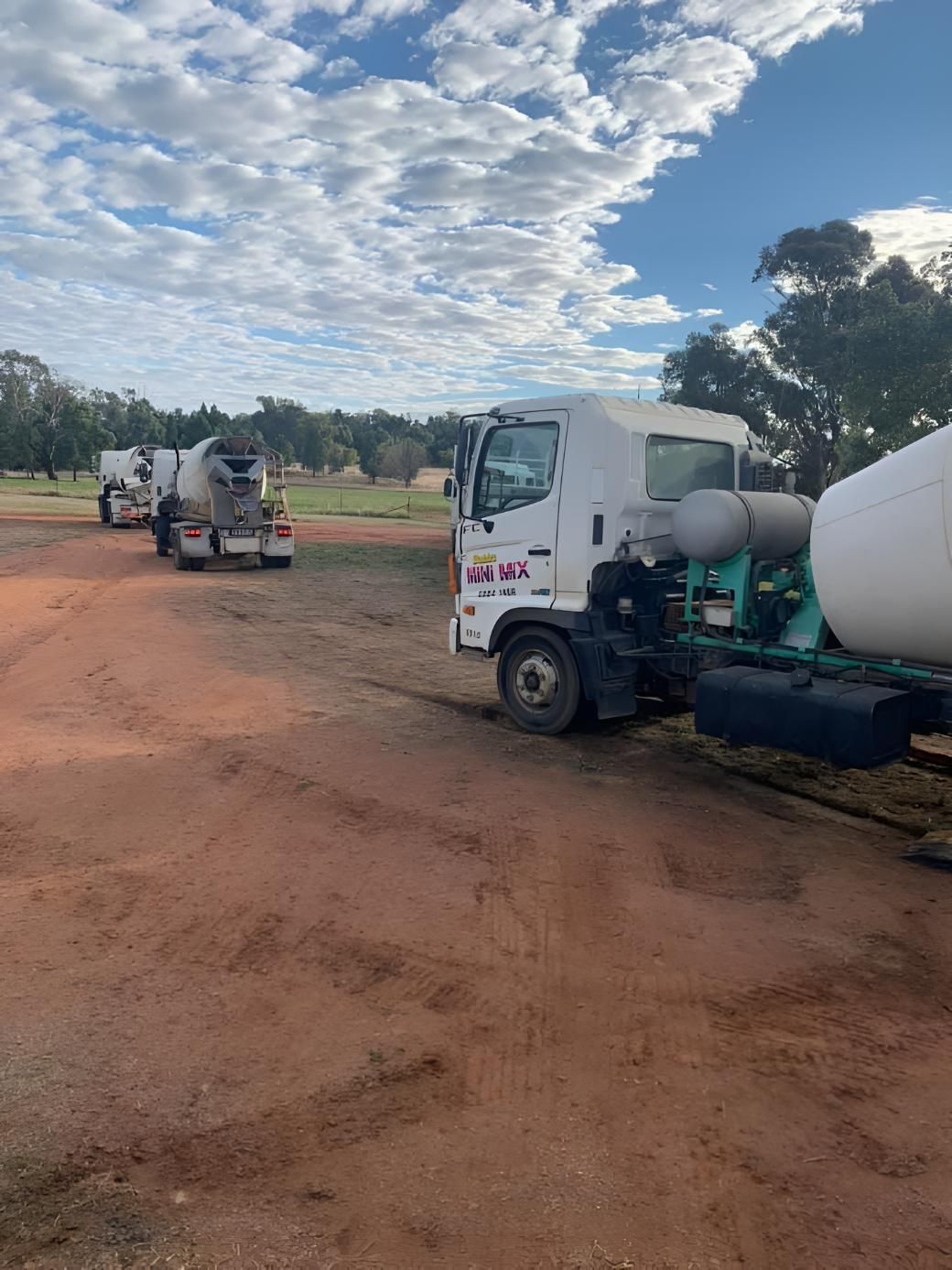 Concrete trucks are parked in a dirt field — Dubbo Mini Mix & Landscape Supplies In Dubbo, NSW