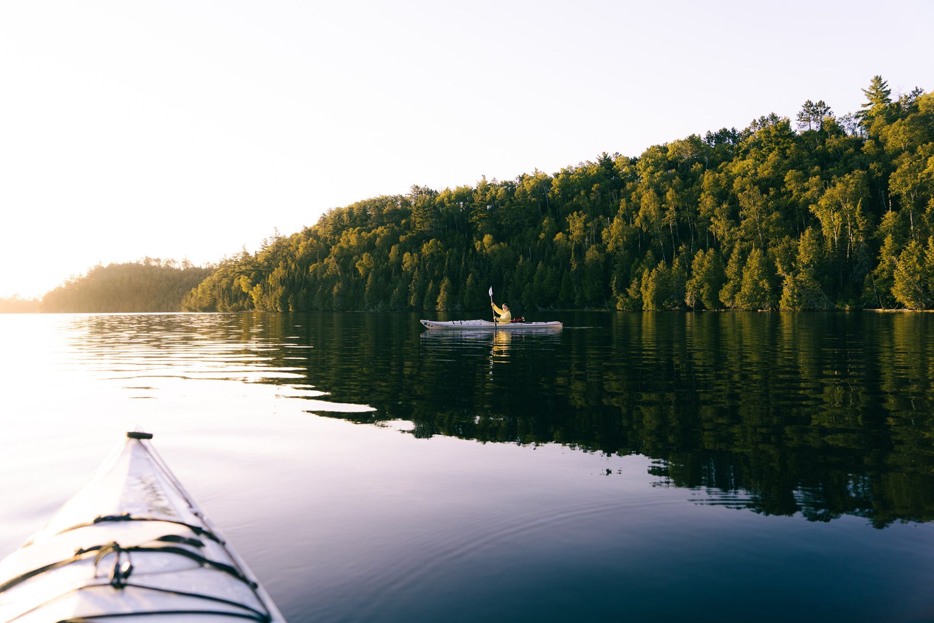 kayaker on the water by the shoreline during sunset