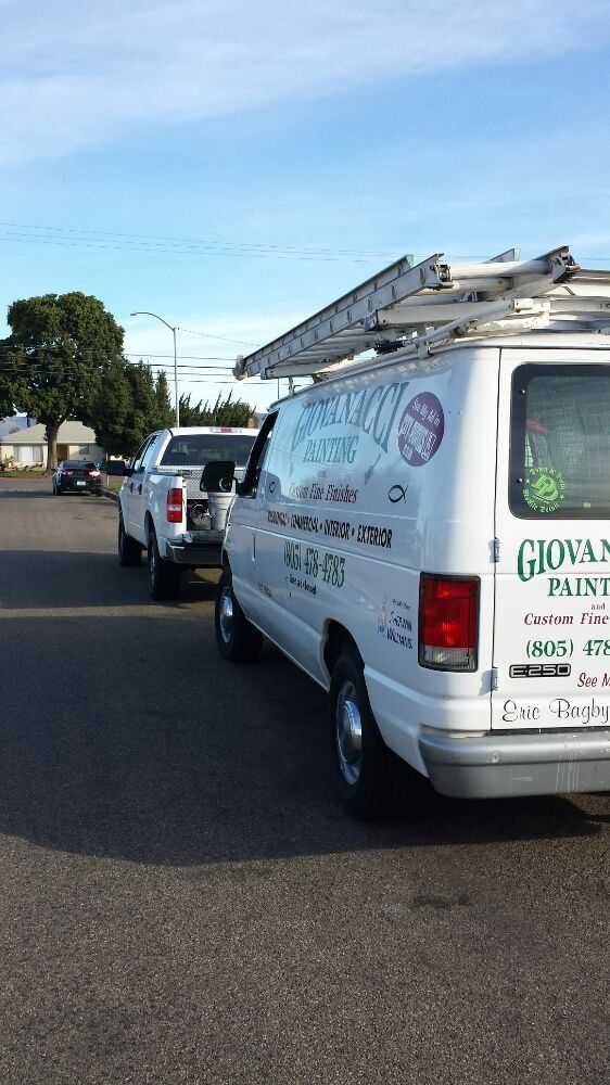 A white van with a ladder on top of it is parked on the side of the road.