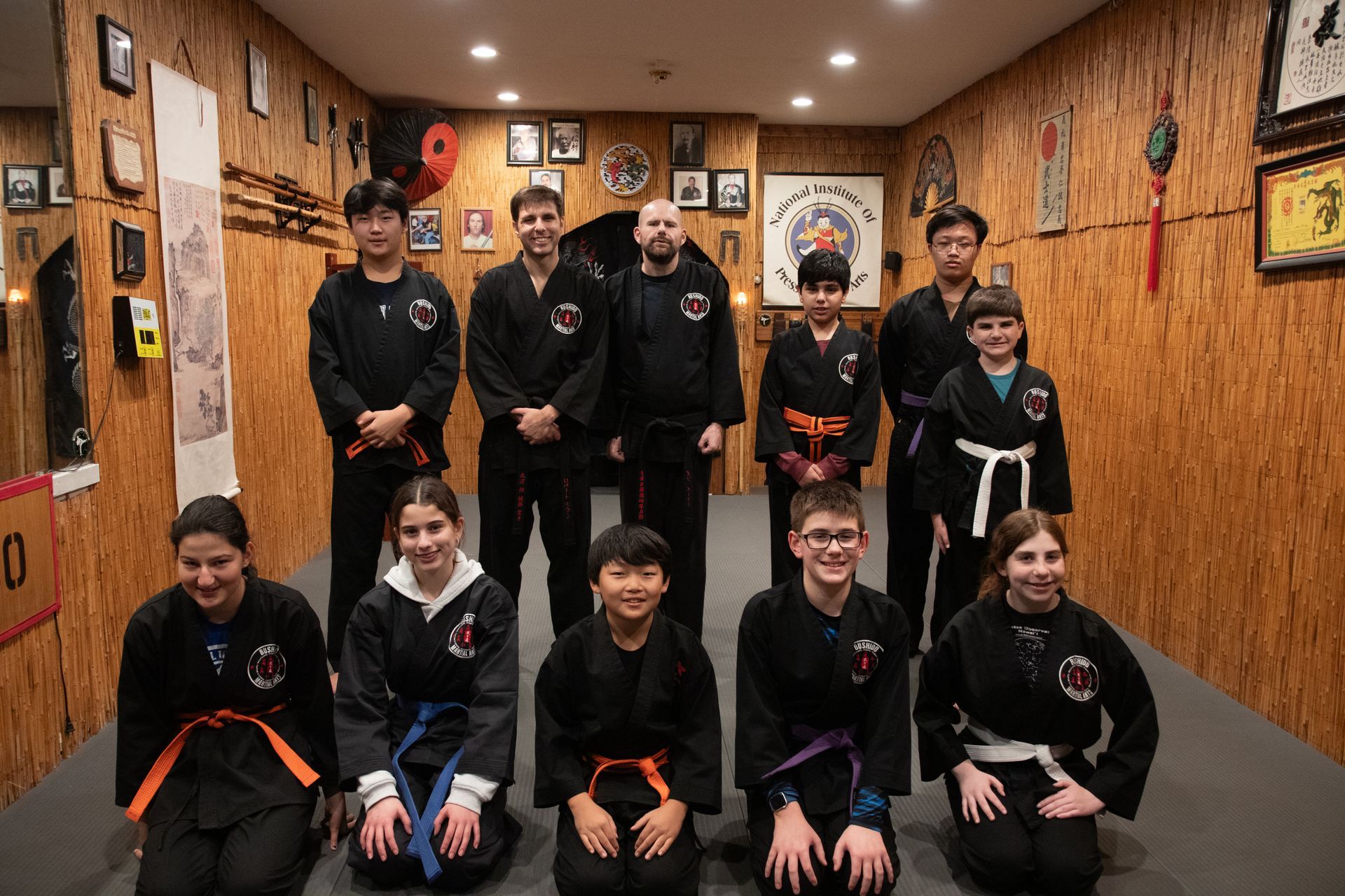 A group of young people are posing for a picture in a martial arts studio.