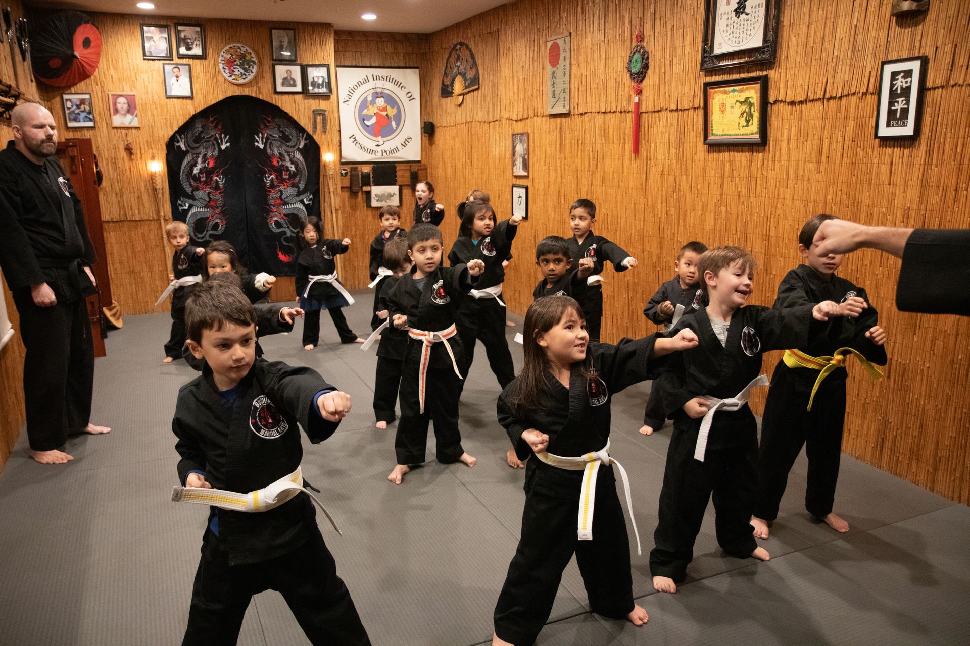 A group of children are practicing martial arts in a gym.