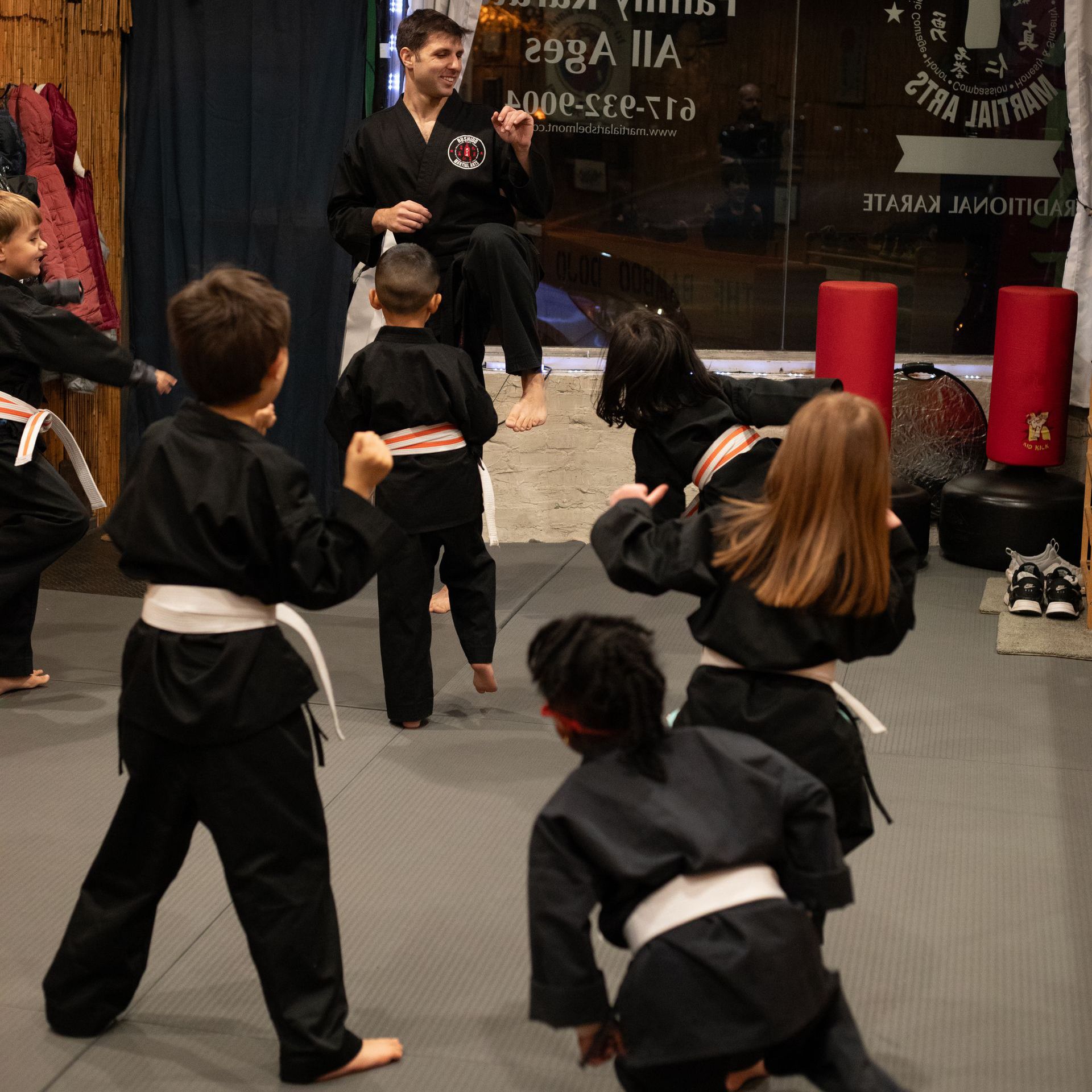 A group of kids are practicing martial arts in front of a sign that says 798 ia