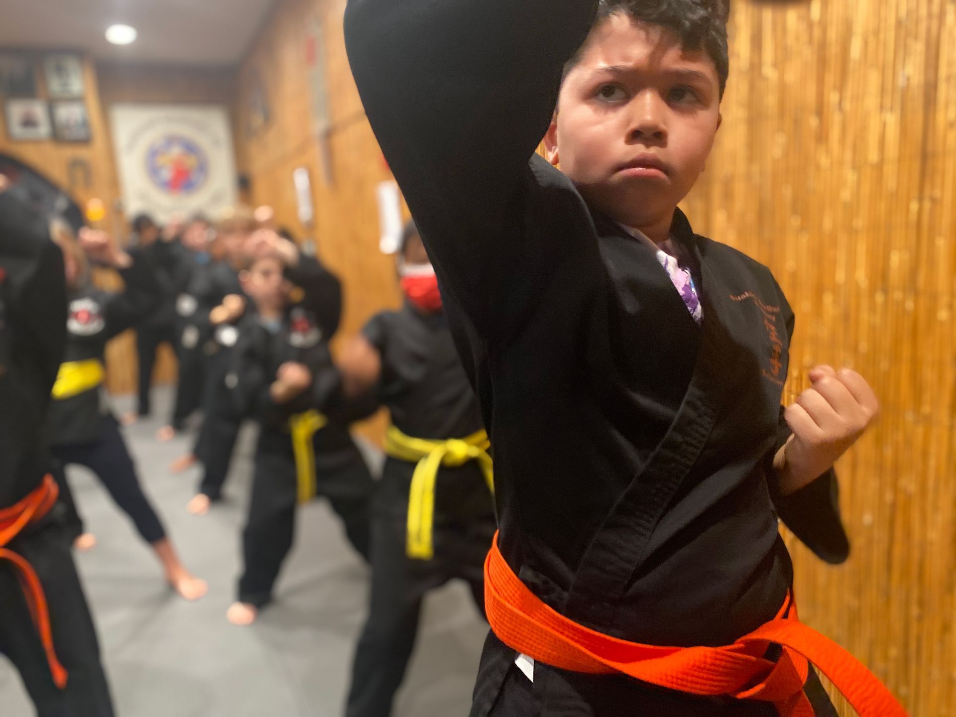 A group of children are practicing martial arts in a gym.