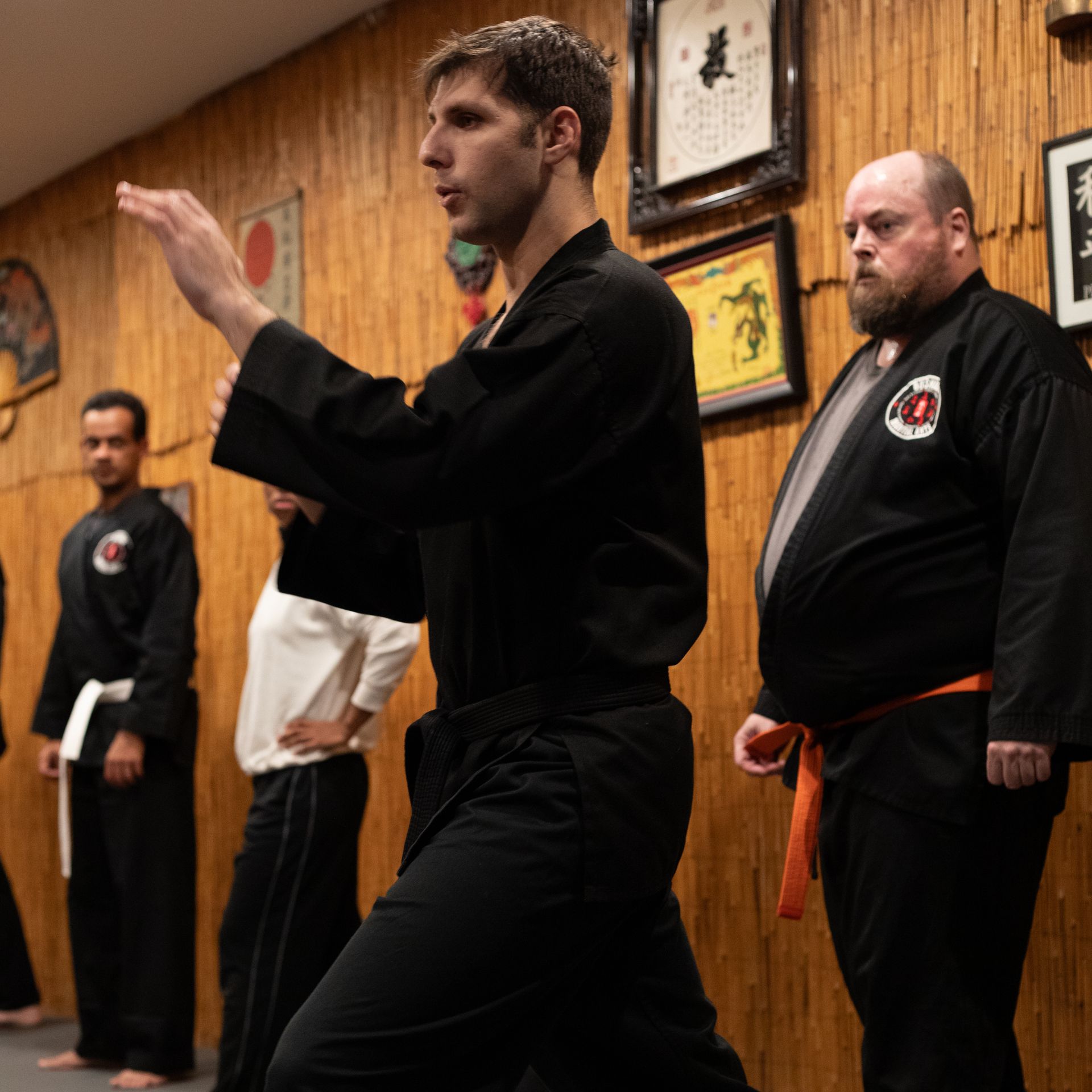 A group of men are practicing martial arts in front of a wooden wall